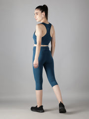 Rear view of Waylene's teal blue capri track suit set, modeled in a turning pose that highlights the racerback sports bra and form-fitting capris, perfect for athletic activities.
