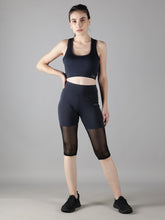 Waylene's navy blue sports bra and capri tights set, featuring a model standing with hands on hips, showcasing the mesh panels and comfortable fit suitable for gym and yoga.
