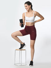 Waylene wine-colored high-performance shorts with pocket, women's activewear, model holding a bottle.