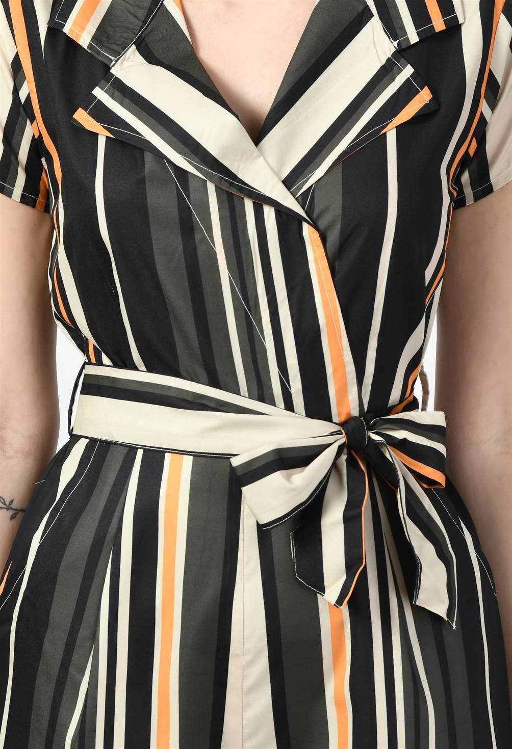 Close-up of Waylene's striped jumpsuit detailing the v-neckline, tie waist, and multi-color pattern. Focus on the texture and fit of the garment.